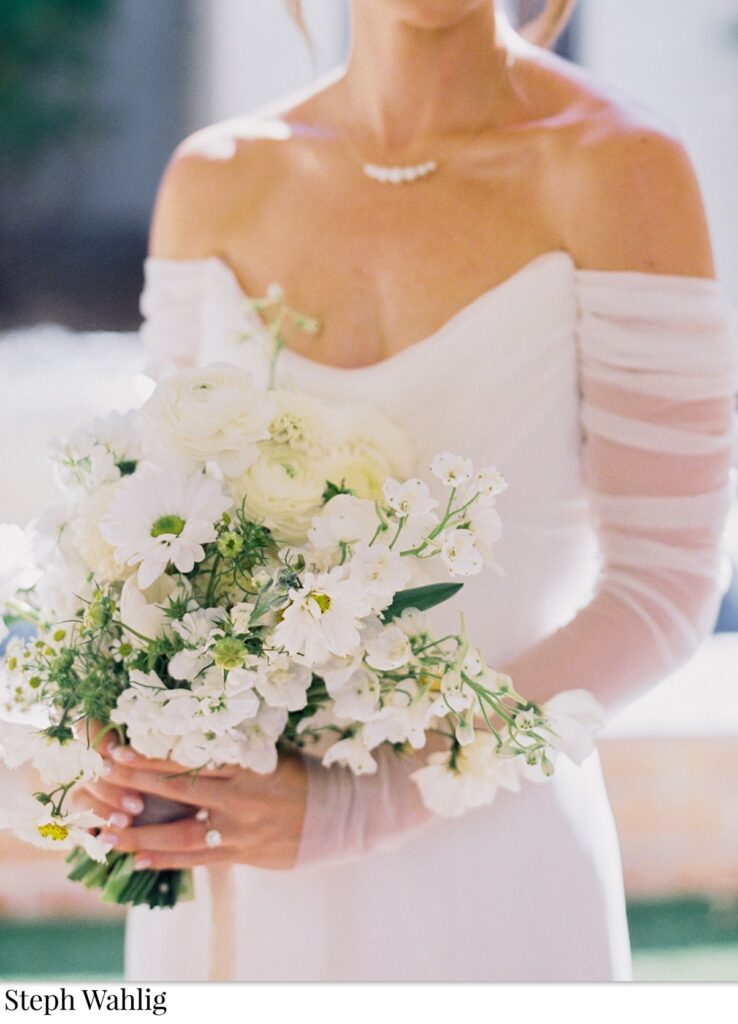 Bride holding bouquet of white flowers.