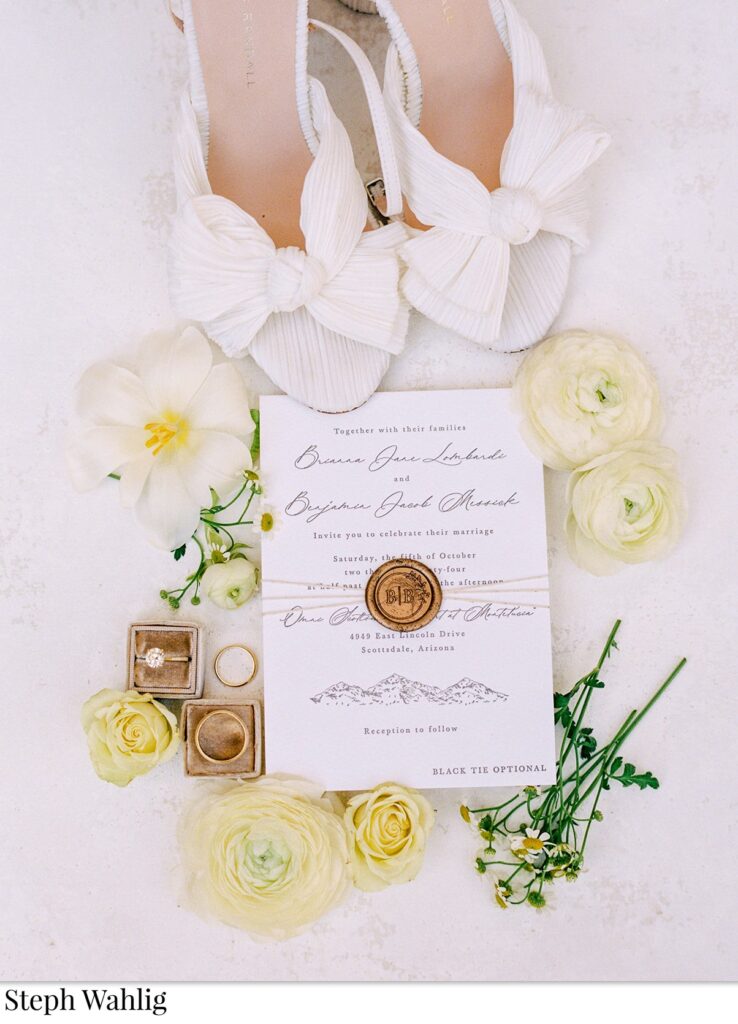 Wedding details flat lay of rings, shoes, invitation.
