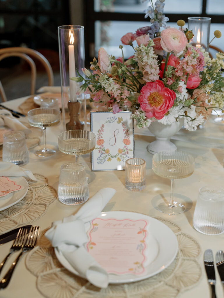 Wedding reception table with floral centerpiece of pink and white shades and cream linens.
