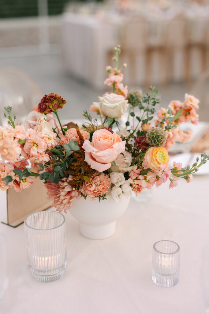 Wedding reception centerpiece of pink, burgundy, and orange colored flowers.