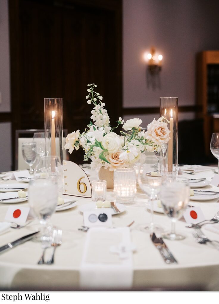 Wedding reception small floral centerpiece with votive candles and taper candles by it.