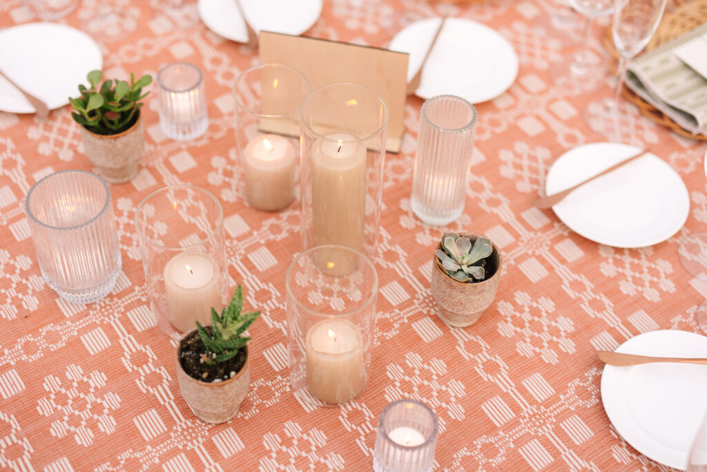 Wedding reception centerpiece design of pillar candles and votive candles with potted succulents.