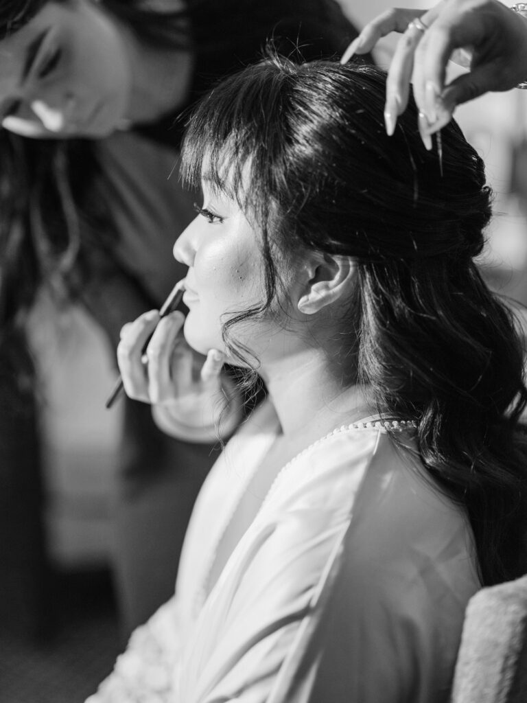 Makeup artist applying makeup to bride's face.