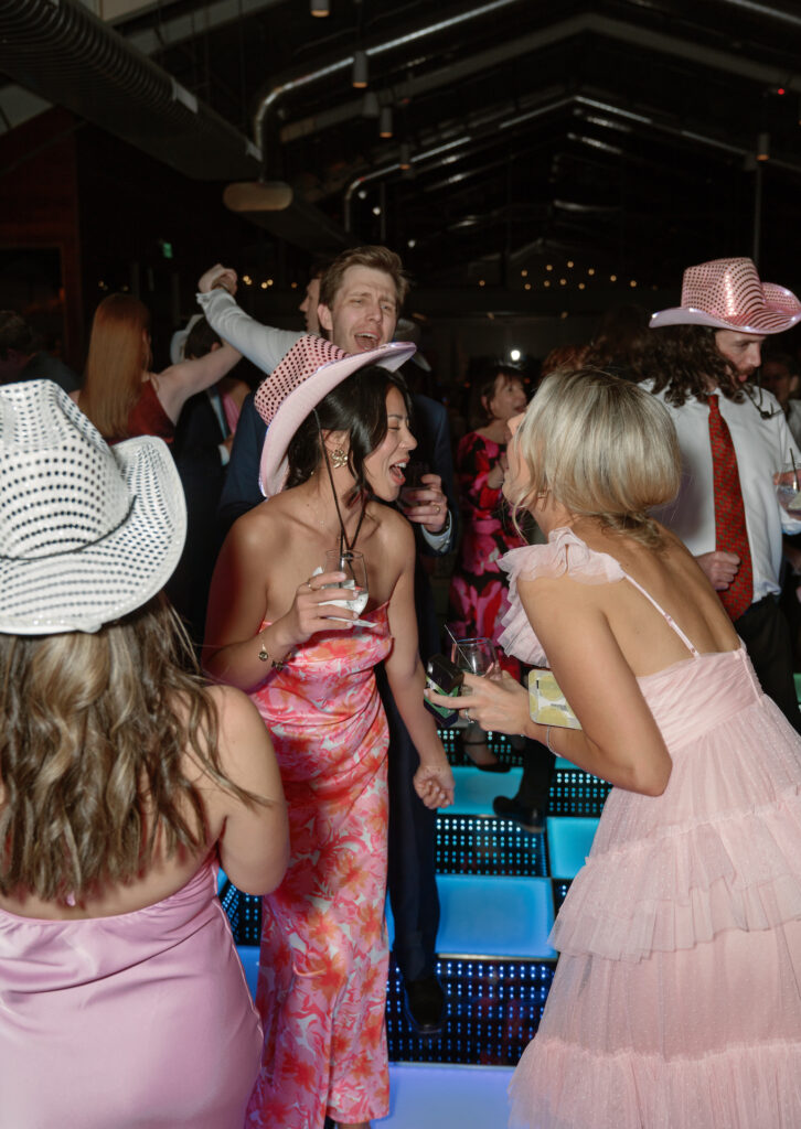 Wedding reception dance with guests on lit dance floor.