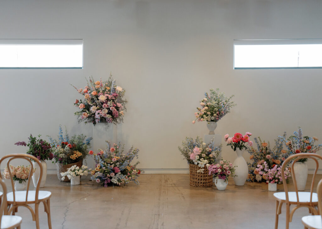 Wedding ceremony floral arrangements for altar space in varying vessels and at different heights.