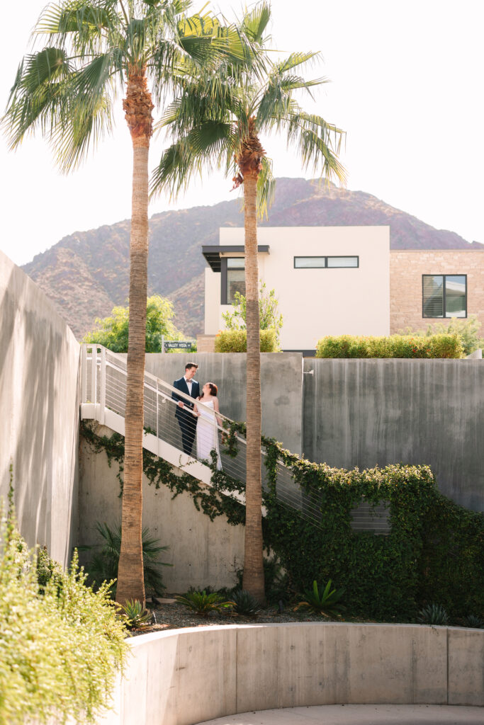 Bride and groom standing on stairs at Mountain Shadows resort, looking at each other.
