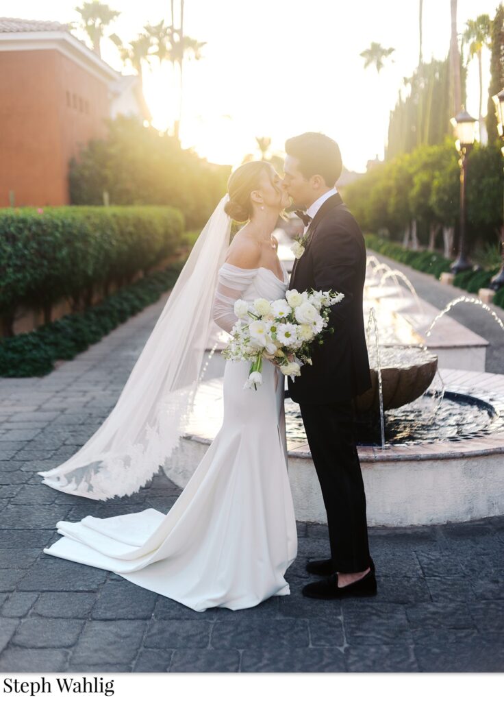 Bride and groom kissing in front of fountain at Omni Resort.