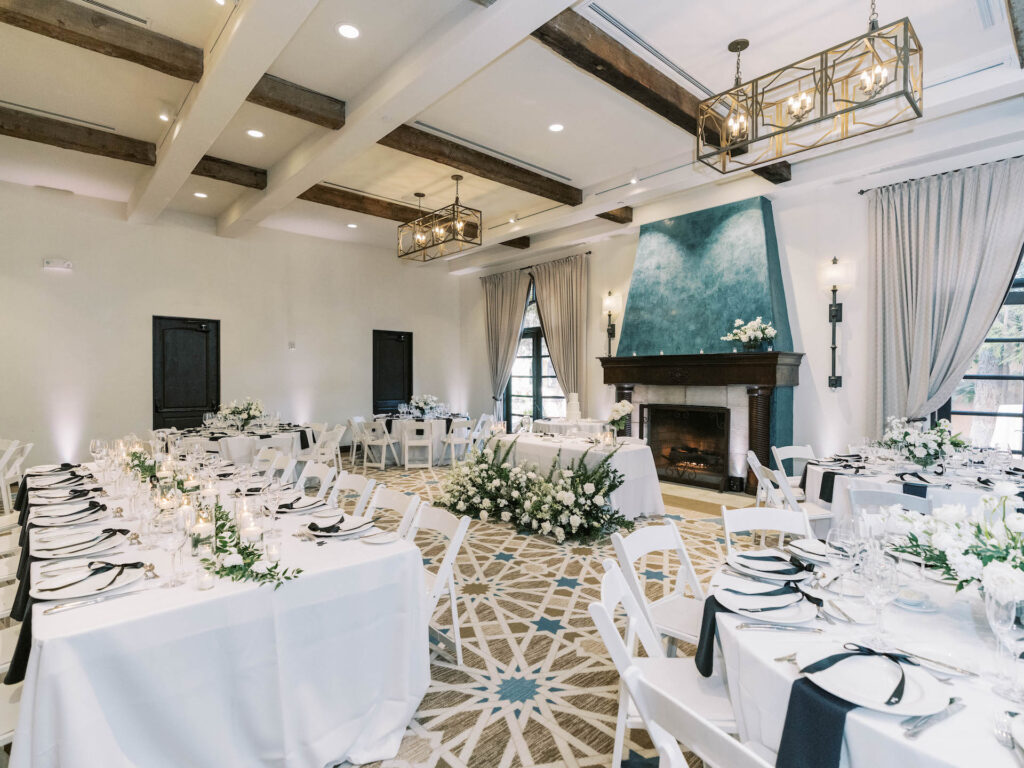 Royal Palms indoor wedding reception space set with white floral designs, and white and blue place settings.