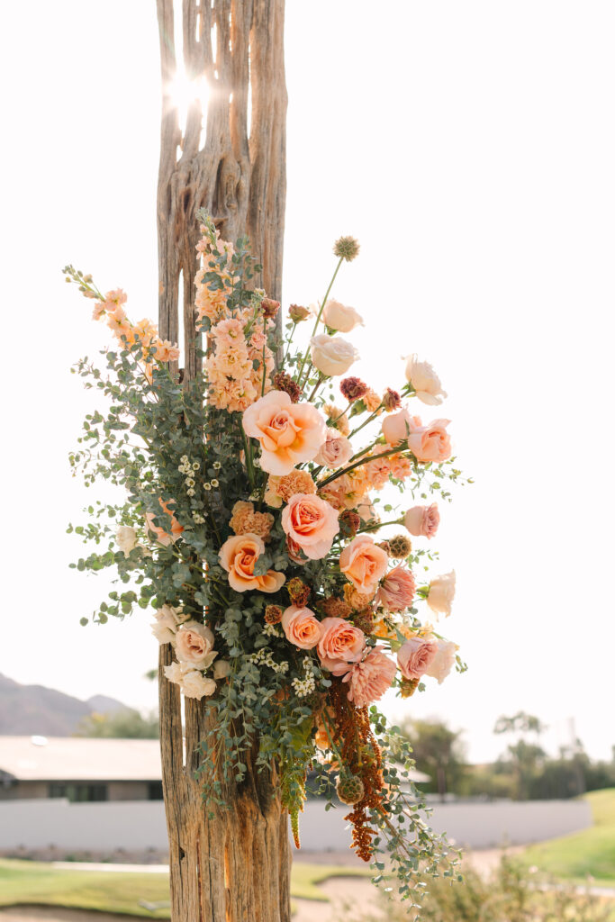 Floral arrangement of pink and peach colors attached to saguaro rib wedding ceremony altar design.