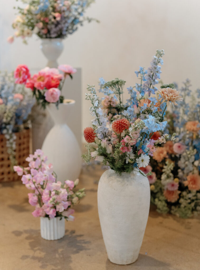 Wedding ceremony altar space design of floral arrangements in various vessels at different levels.