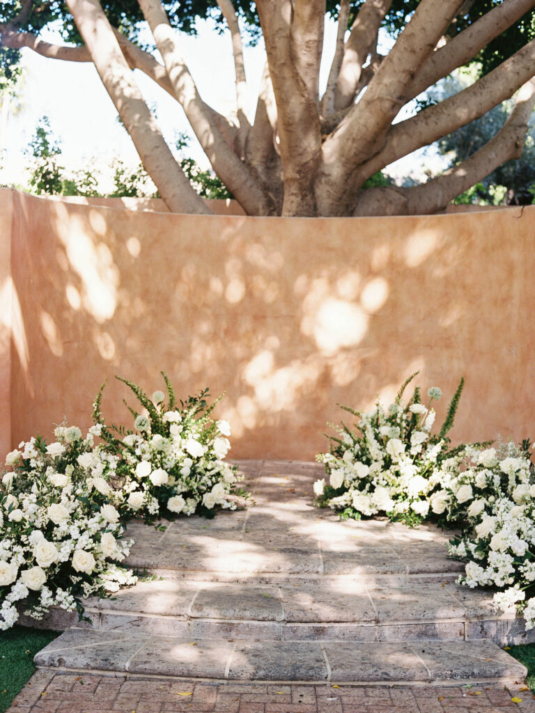 Ceremony altar space ground floral designs of white flowers and greenery.