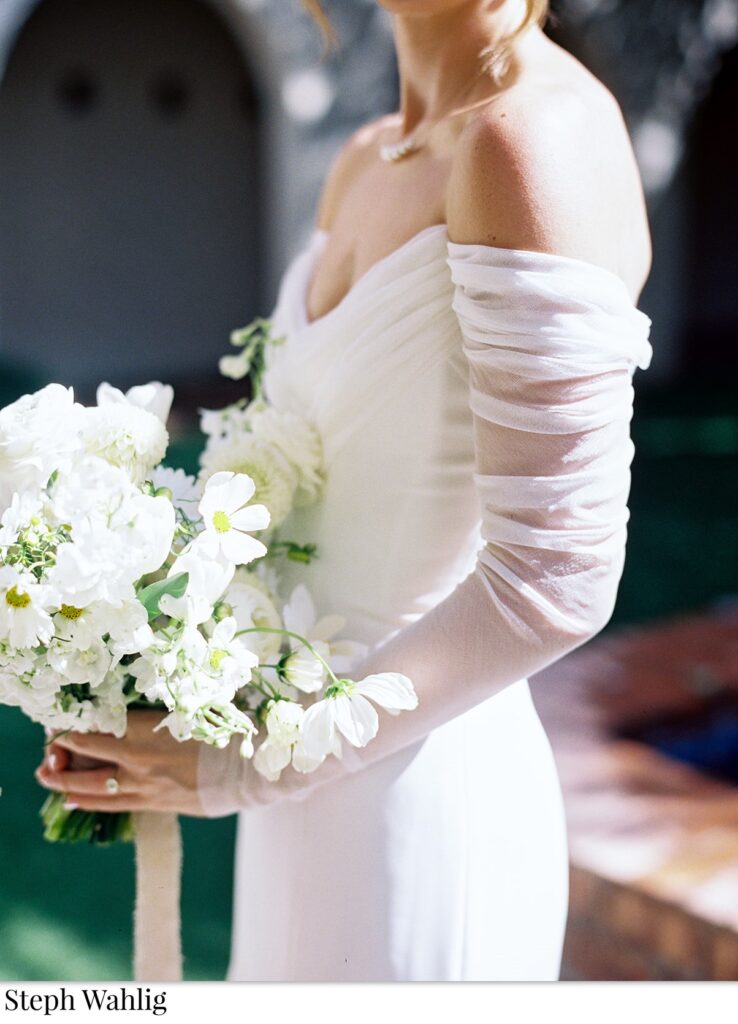 Bride holding bouquet of white flowers.