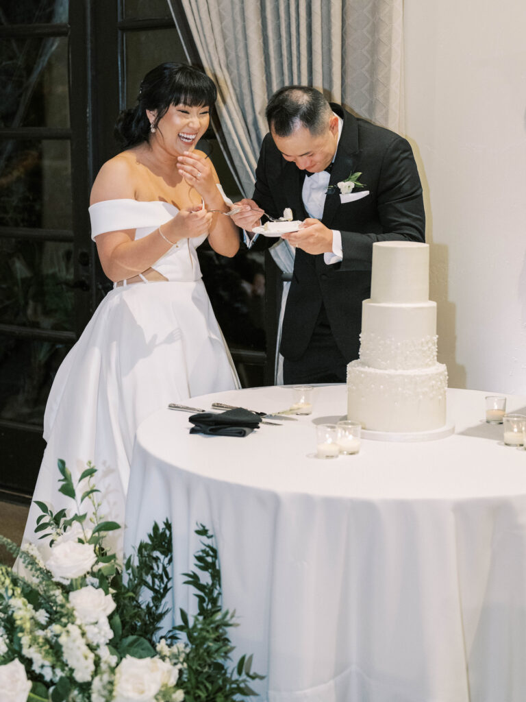 Bride and groom eating cake after cutting at wedding reception.