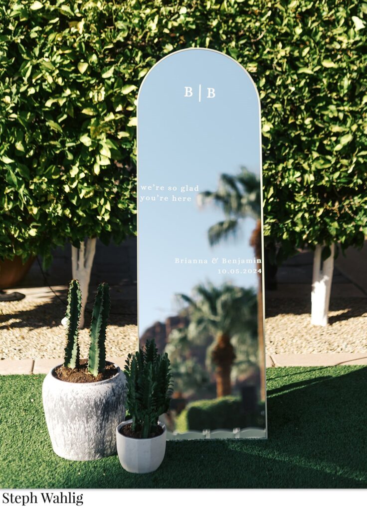 Mirror welcome sign with potted cacti on the ground next to it