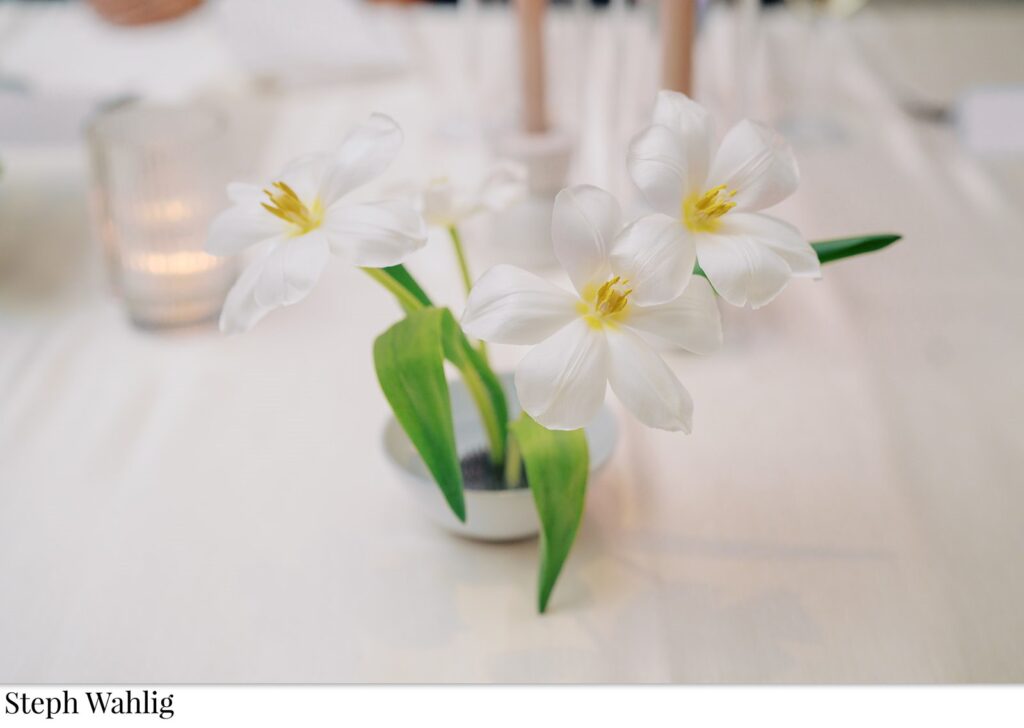 White flowers in flower frog in small bowl for reception centerpiece.