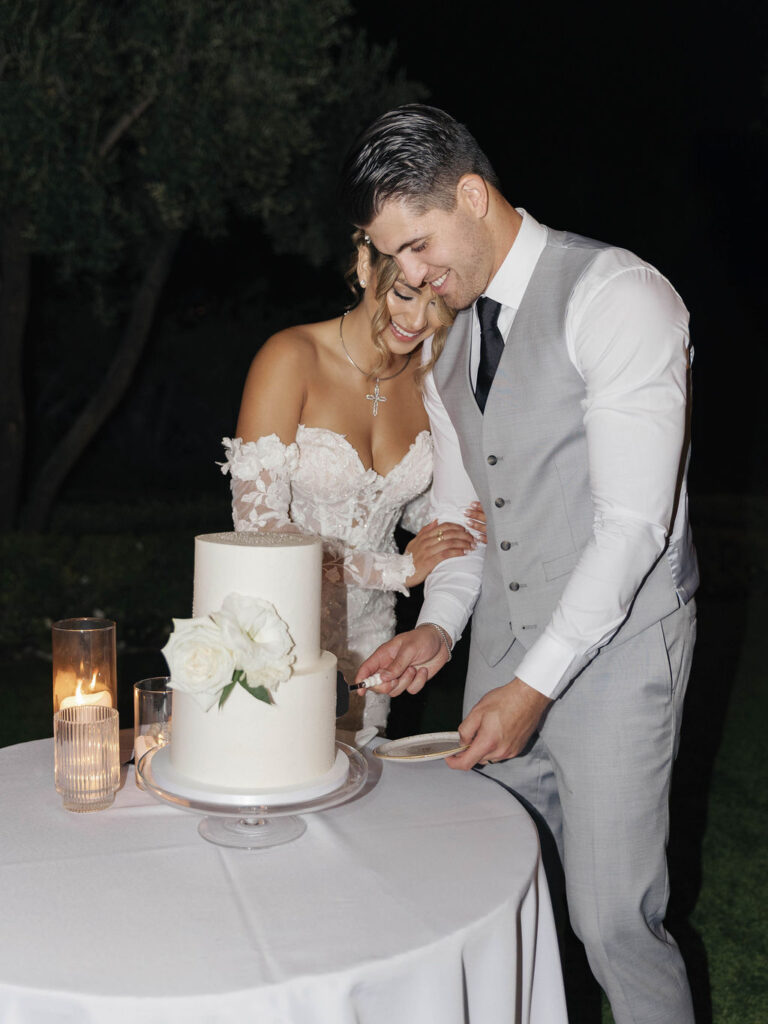 Bride and groom cutting a two tiered white wedding cake.