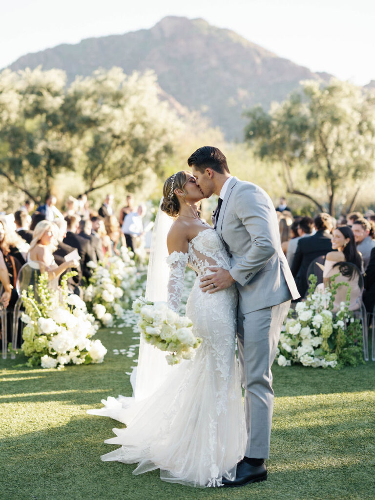 Bride and groom kissing at back of wedding ceremony outside at El Chorro.