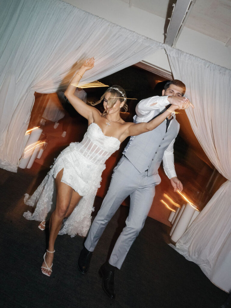 Bride and groom holding hands above their head, entering the reception.