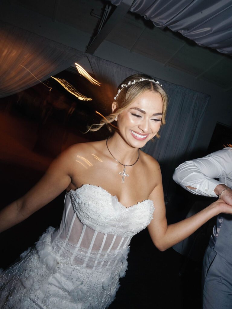 Bride smiling, walking and holding hands with groom inside.