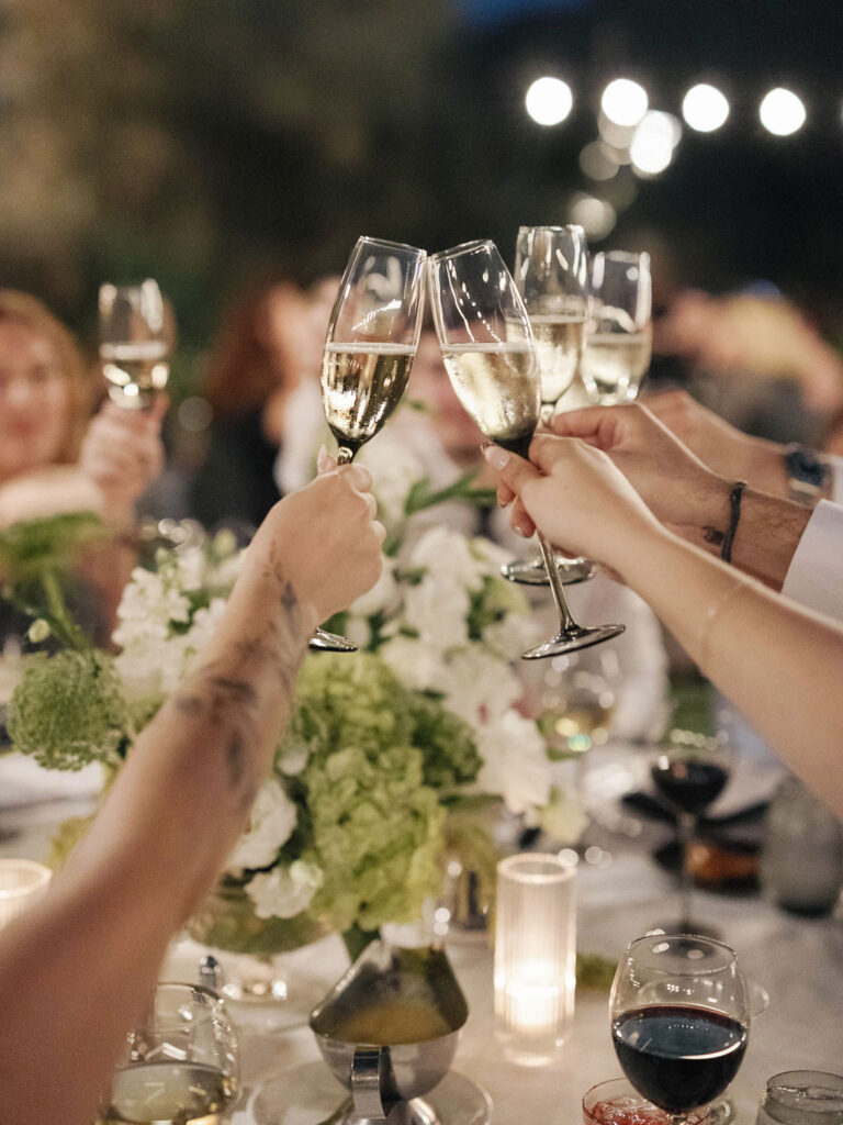 Guests at wedding reception holding up glasses of champagne for a toast.