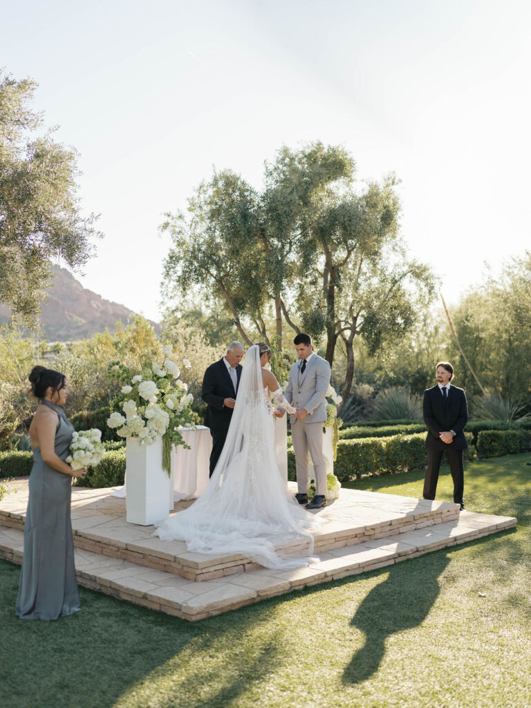 Bride and groom at wedding ceremony altar space holding hands with officiant standing behind them.