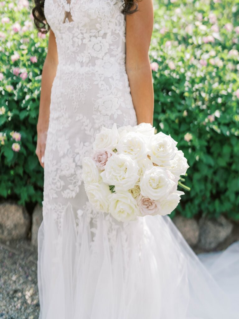 Tight bridal bouquet of white and blush roses.