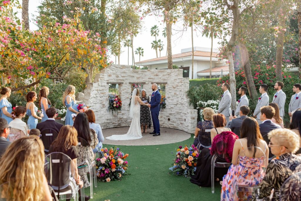 Bride and groom in ceremony altar space during ceremony at The Scott, holding hands and facing each other with officiant standing behind them.