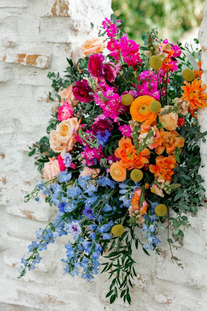 Ceremony floral design with floral arrangement placed in window cut out of brick curved wall.
