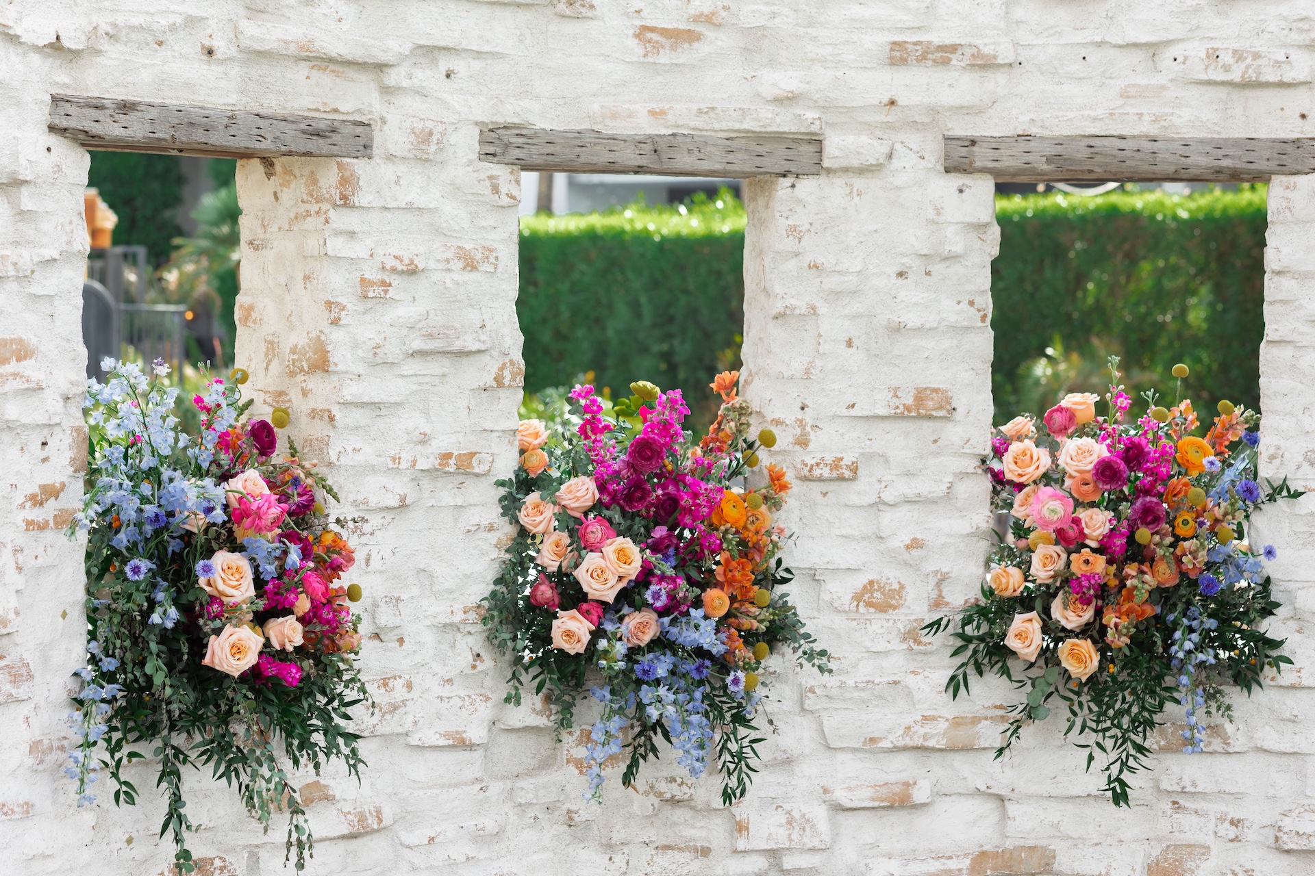 Ceremony floral design with floral arrangements placed in window cut outs of brick curved wall.