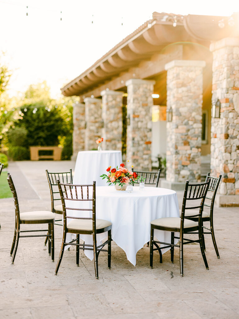 Cocktail hour space with low table in front and high table in back, both with floral centerpeices on them.