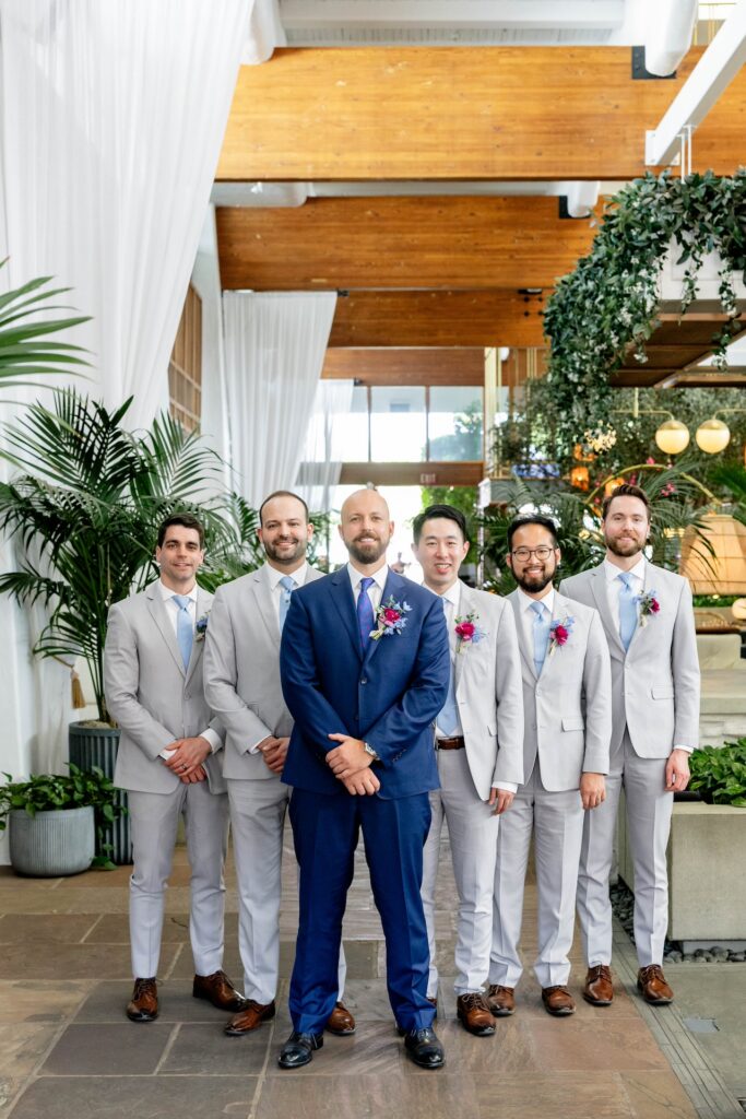 Groom standing in row with groomsmen all wearing boutonnieres.