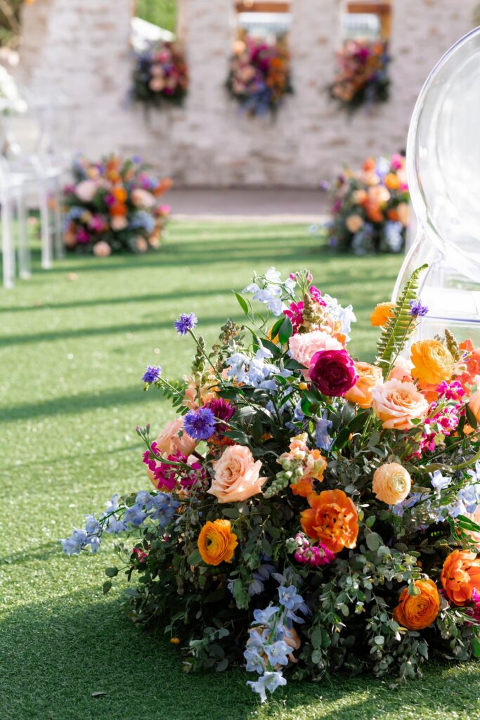 Ground floral next to guest chairs during outdoor wedding ceremony.